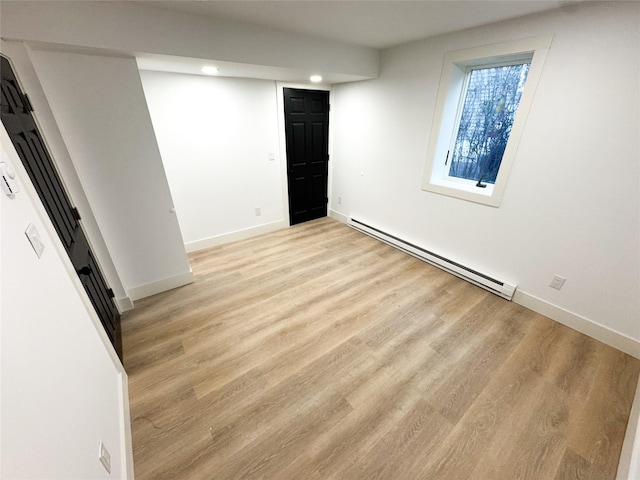 empty room with light hardwood / wood-style floors and a baseboard heating unit