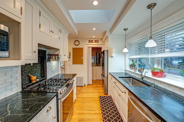 kitchen with pendant lighting, appliances with stainless steel finishes, plenty of natural light, light hardwood / wood-style floors, and white cabinetry