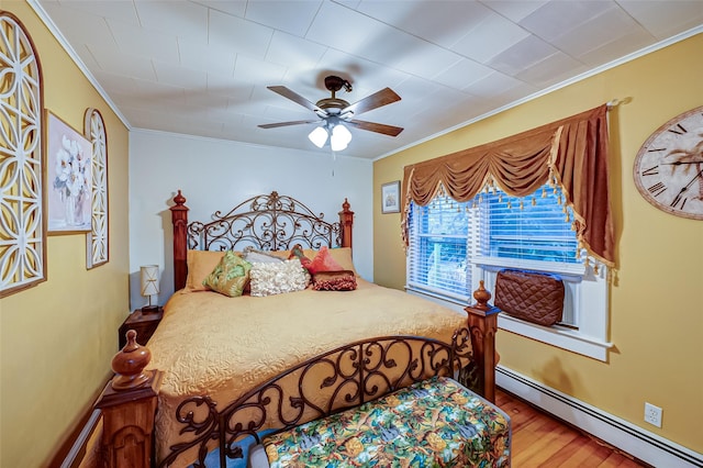 bedroom featuring ceiling fan, ornamental molding, wood-type flooring, and a baseboard heating unit