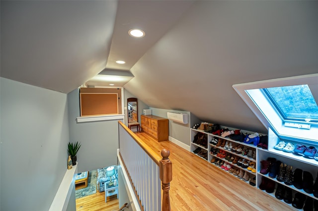 additional living space featuring vaulted ceiling with skylight and wood-type flooring