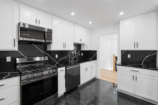 kitchen featuring dark stone counters, sink, appliances with stainless steel finishes, tasteful backsplash, and white cabinetry