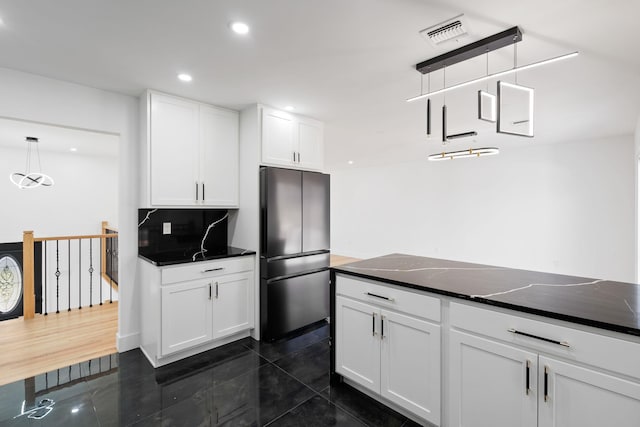 kitchen with white cabinetry, stainless steel fridge, dark tile patterned floors, and decorative light fixtures