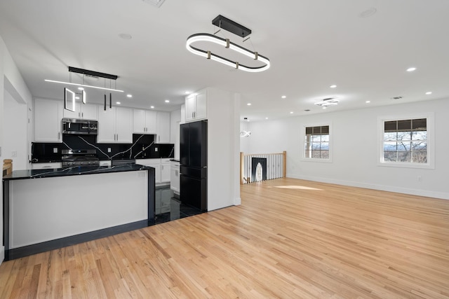 kitchen featuring white cabinets, hanging light fixtures, light hardwood / wood-style flooring, appliances with stainless steel finishes, and tasteful backsplash