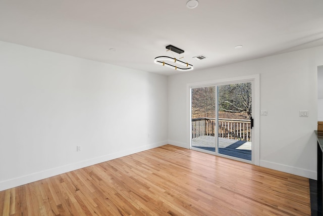 empty room featuring light wood-type flooring and an inviting chandelier