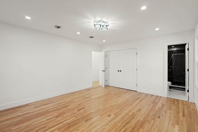 unfurnished bedroom with light wood-type flooring, a closet, and connected bathroom