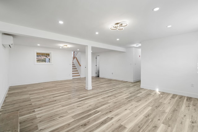 basement with light hardwood / wood-style flooring and an AC wall unit