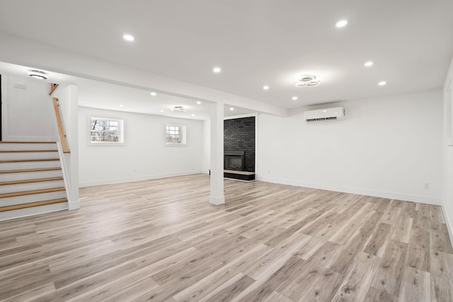 basement featuring light hardwood / wood-style flooring, a wall mounted air conditioner, and a brick fireplace