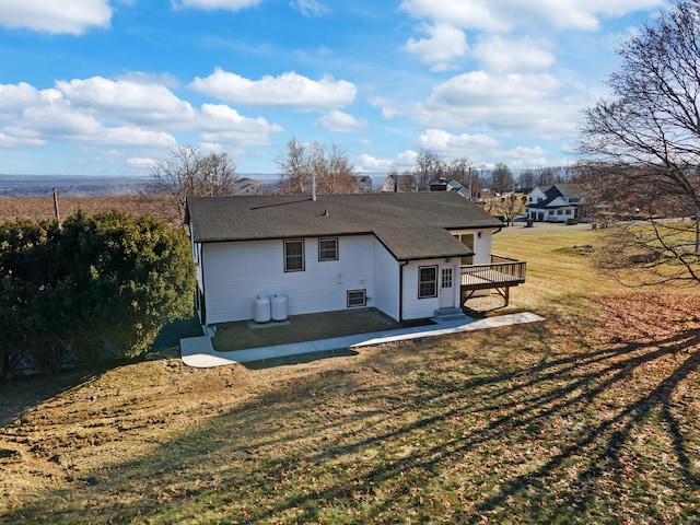 rear view of property featuring a wooden deck, a yard, and a patio