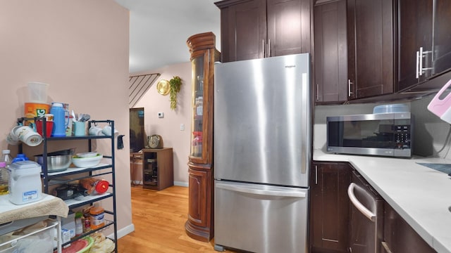 kitchen with dark brown cabinets, light wood-type flooring, and appliances with stainless steel finishes