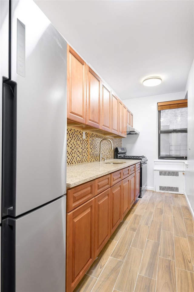 385 Argyle Rd Unit 2K, Brooklyn, NY 11218 - kitchen with appliances with stainless steel finishes, radiator, decorative backsplash, light wood-type flooring, and light stone countertops