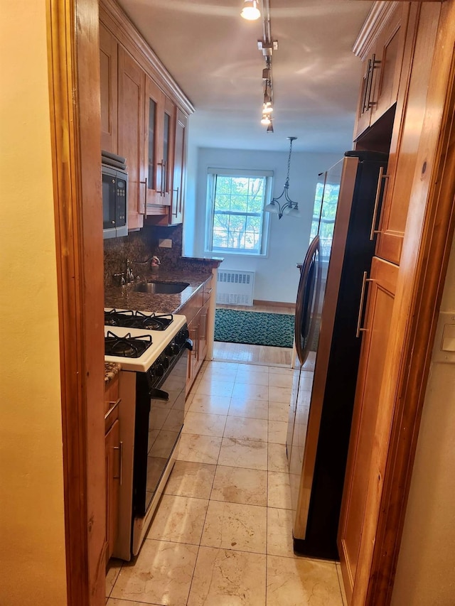 149-30 88th St Unit 4A, Howard Beach, NY 11414 - kitchen with appliances with stainless steel finishes, brown cabinetry, radiator heating unit, rail lighting, and glass insert cabinets