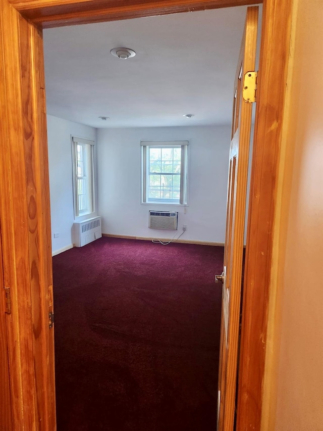 spare room with radiator heating unit, carpet floors, and a wall unit AC