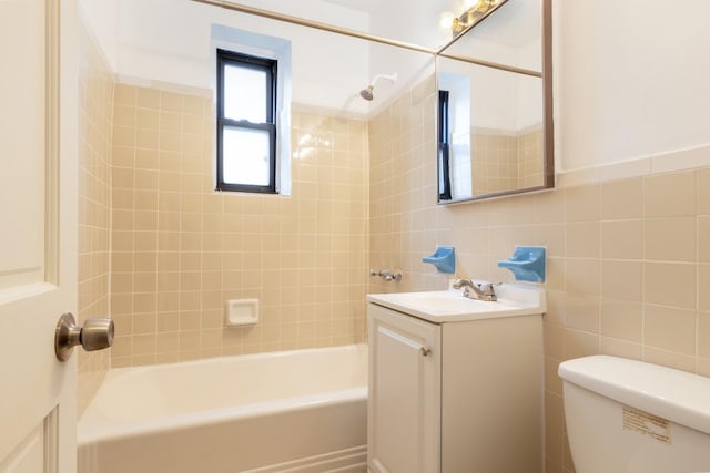 full bathroom featuring vanity, tiled shower / bath combo, toilet, and tile walls