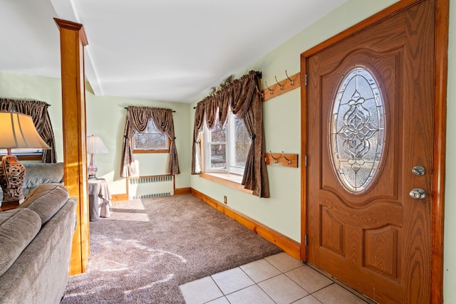 foyer featuring light tile patterned floors, radiator heating unit, baseboards, and light colored carpet