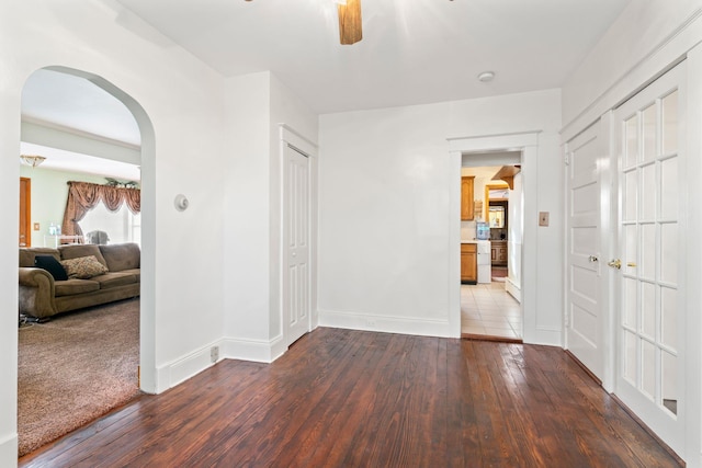 unfurnished room with arched walkways, a ceiling fan, hardwood / wood-style flooring, and baseboards