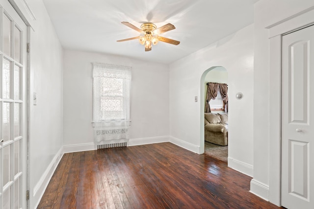 interior space featuring arched walkways, baseboards, ceiling fan, and hardwood / wood-style floors