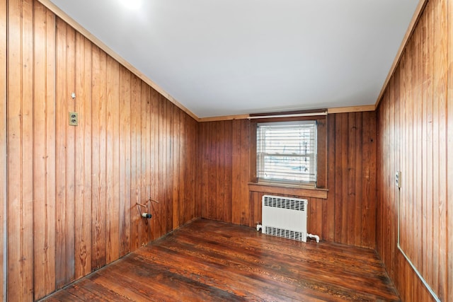 spare room with radiator, wood walls, and hardwood / wood-style floors