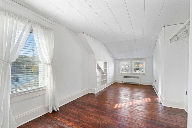 bonus room with built in shelves, lofted ceiling, radiator heating unit, wood finished floors, and baseboards