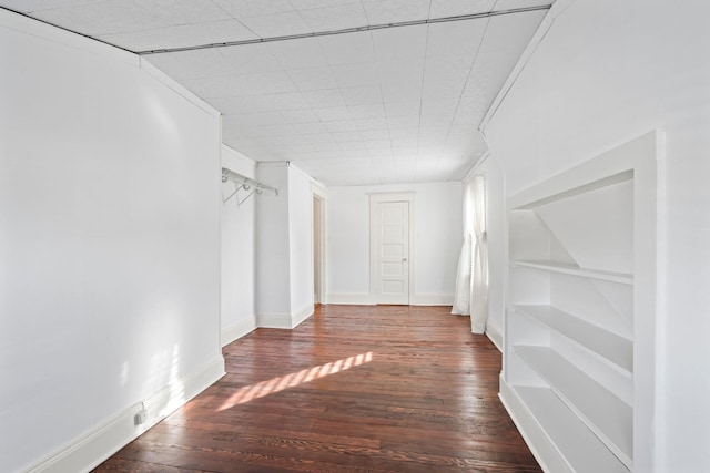 spare room featuring built in features, wood-type flooring, and baseboards