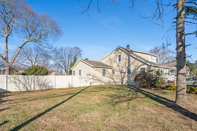 rear view of property with a yard, fence, and a chimney