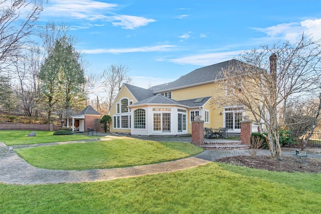 rear view of house with a sunroom and a yard