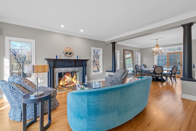 living room with wood-type flooring, a wealth of natural light, crown molding, and a notable chandelier