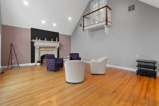 sitting room featuring high vaulted ceiling and wood-type flooring