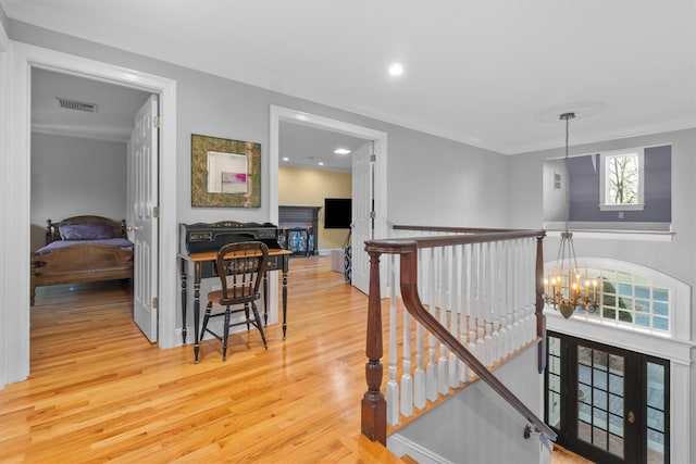 hall featuring a wealth of natural light, wood-type flooring, and an inviting chandelier