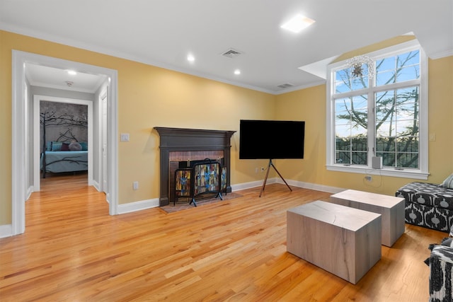 living room with crown molding, a fireplace, and light hardwood / wood-style floors