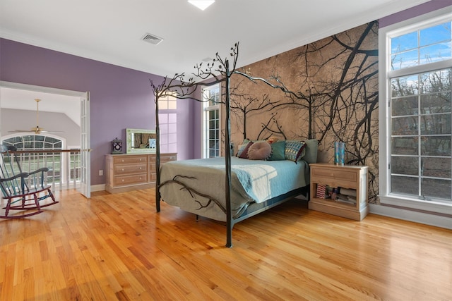 bedroom with light wood-type flooring, vaulted ceiling, and ornamental molding