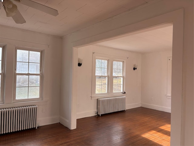 empty room with plenty of natural light, dark hardwood / wood-style floors, and radiator heating unit