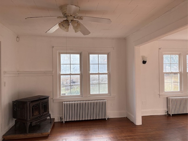 spare room with a healthy amount of sunlight, radiator heating unit, and a wood stove