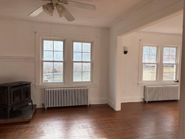 spare room featuring a wood stove, radiator heating unit, and plenty of natural light