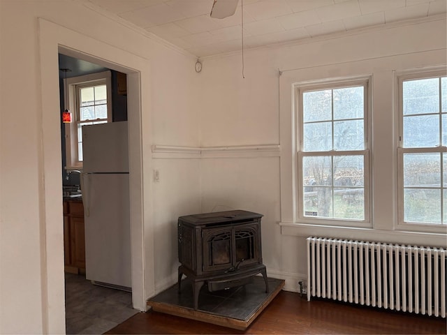 interior space featuring a wood stove, radiator, white refrigerator, hardwood / wood-style flooring, and ornamental molding