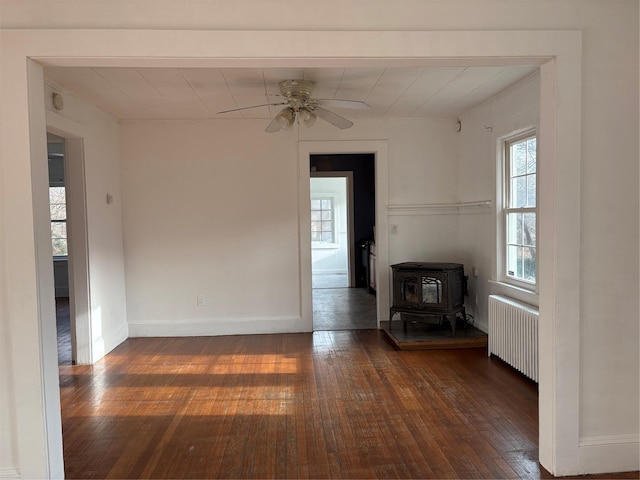 unfurnished living room with plenty of natural light, dark hardwood / wood-style floors, and radiator heating unit