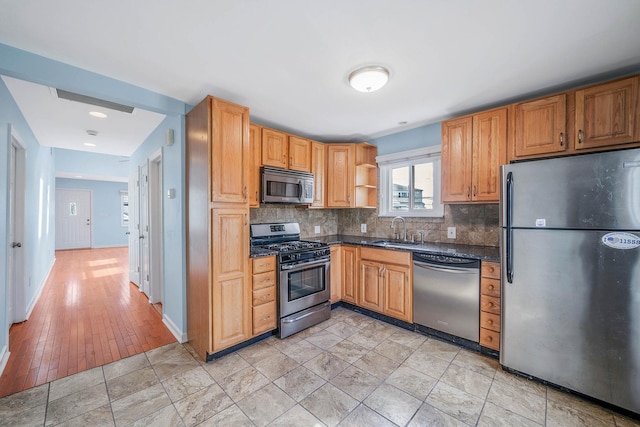 kitchen with appliances with stainless steel finishes, sink, and decorative backsplash