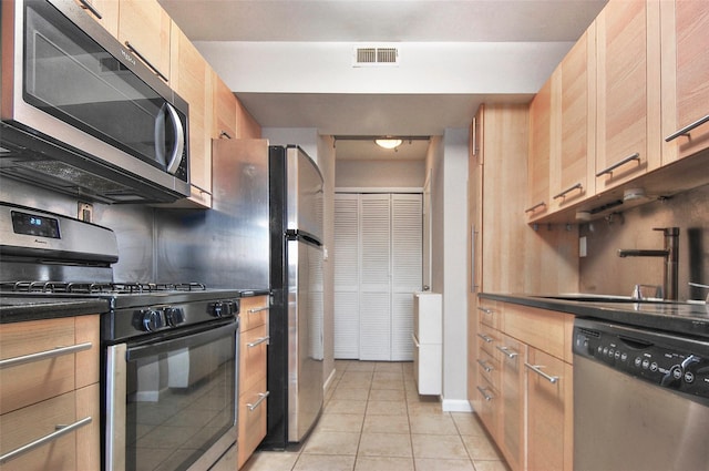 kitchen featuring light brown cabinetry, light tile patterned floors, sink, and appliances with stainless steel finishes