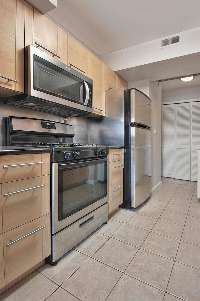 kitchen with light tile patterned floors, stainless steel appliances, and light brown cabinetry