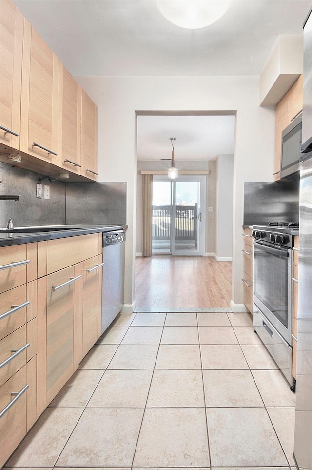 kitchen with tasteful backsplash, light brown cabinets, light tile patterned floors, and appliances with stainless steel finishes