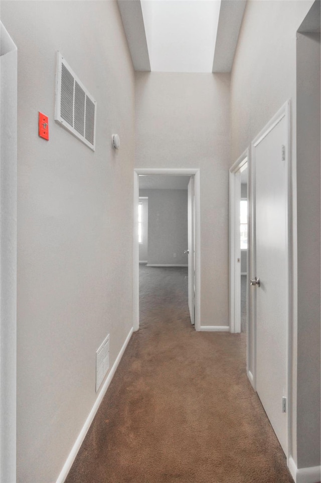 hall with dark carpet and a towering ceiling