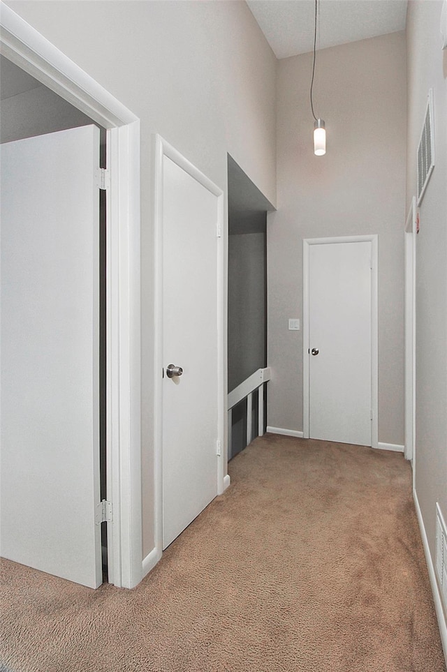 hallway with carpet floors and a high ceiling