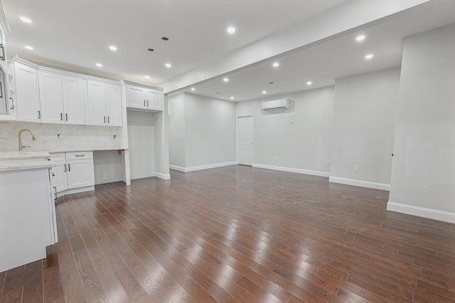 unfurnished living room with dark hardwood / wood-style flooring, sink, and a wall unit AC