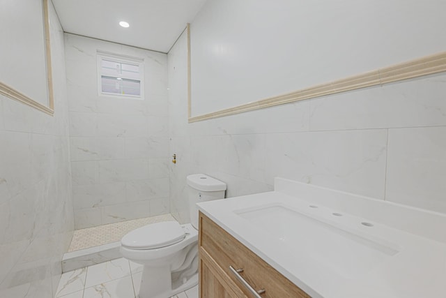 bathroom with vanity, toilet, tile walls, and a tile shower