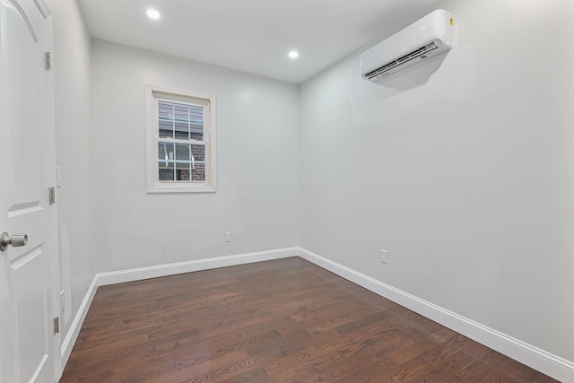 empty room featuring a wall mounted air conditioner and dark hardwood / wood-style flooring