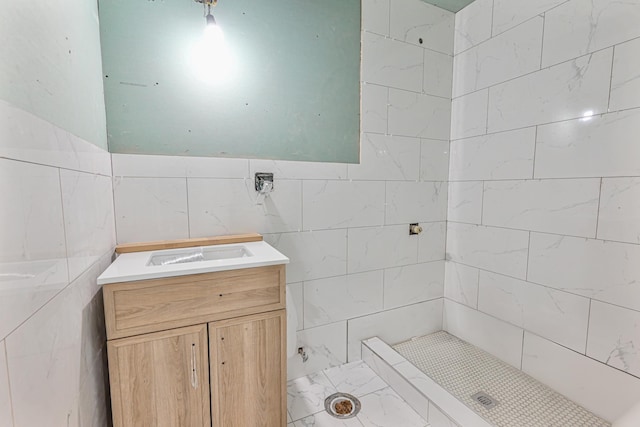 bathroom with tiled shower, vanity, and tile walls