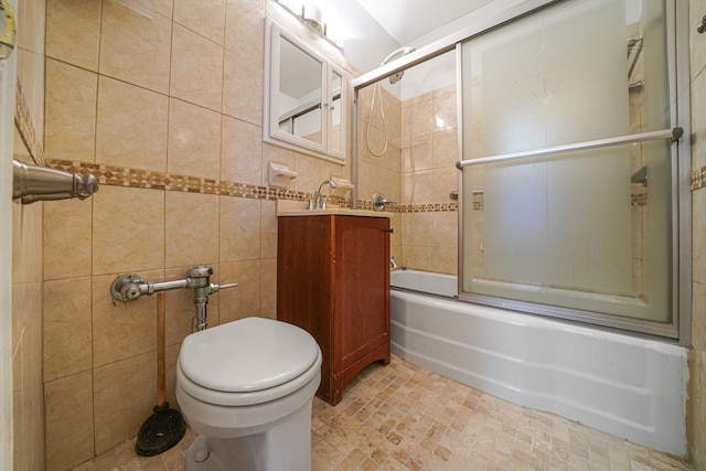 full bathroom featuring vanity, toilet, tile walls, and bath / shower combo with glass door