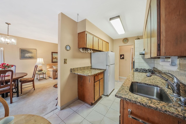 kitchen featuring white refrigerator, sink, decorative backsplash, decorative light fixtures, and stainless steel gas cooktop