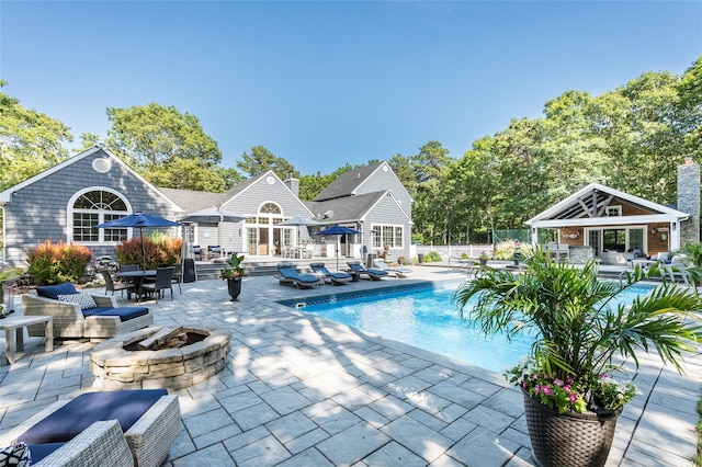 view of pool featuring a fire pit, an outbuilding, and a patio