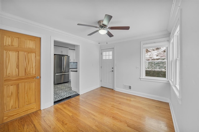 entrance foyer with light hardwood / wood-style floors, a wealth of natural light, crown molding, and ceiling fan