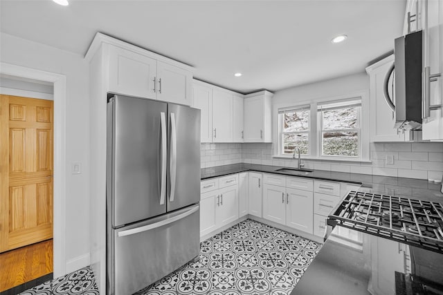 kitchen with decorative backsplash, appliances with stainless steel finishes, white cabinetry, and sink